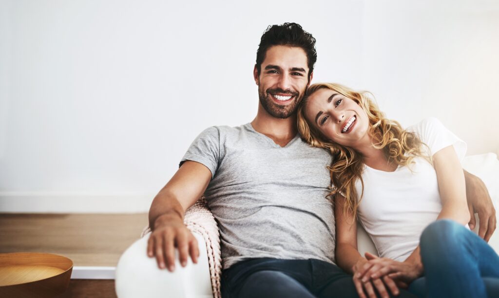 Happy couple sitting on sofa after vasectomy in Los Angeles, CA
